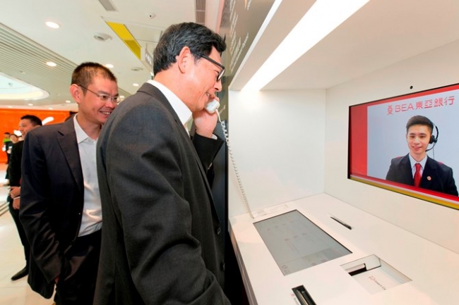 东亚银行副行政总裁李民桥先生向金管局总裁陈德霖先生介绍视像柜员机。